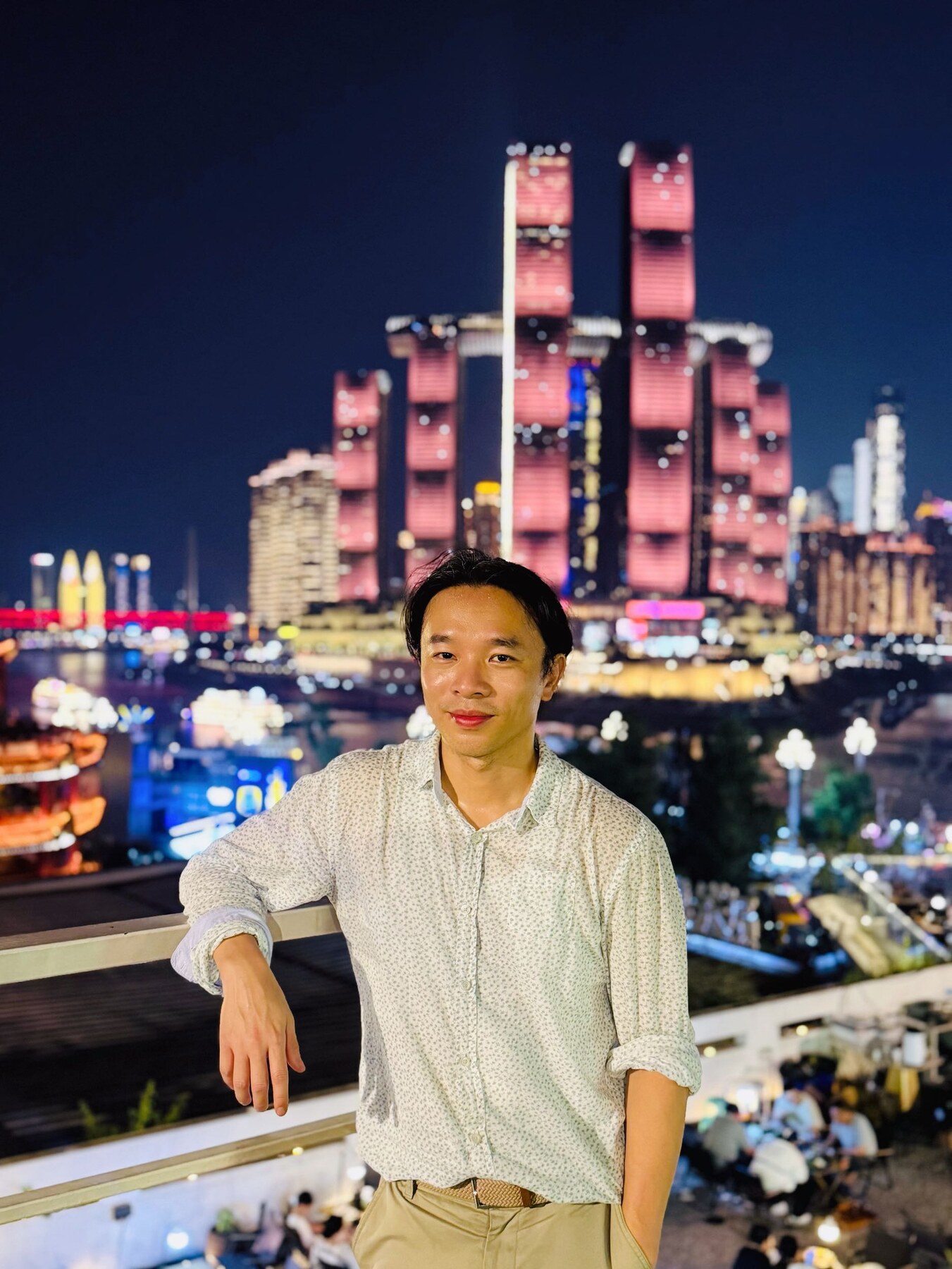張J在逐漸亮起的重慶天際線前留影